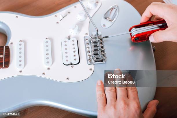 Guitar Master Adjusting Bridge Saddle On Tremolo Of Electric Guitar Using Multitool Stock Photo - Download Image Now