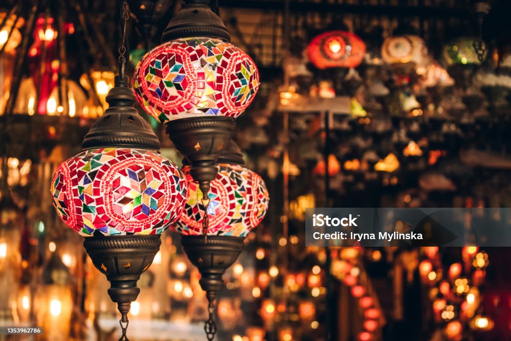 Traditional turkish or moroccan light mosaic lamp. Colorful stained glass lamp against defocused souvenir shop background with copy space. Popular souvenir and ideas for present Traditional turkish or moroccan light mosaic lamp. Colorful stained glass lamp against defocused souvenir shop background with copy space. Popular souvenir and ideas for present. Selective focus Electric Lamp Stock Photo