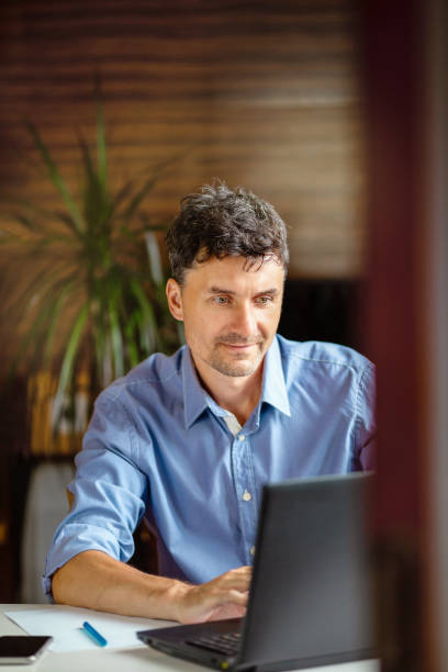 istock Man online works at a computer from home. 1353965000