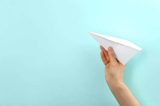 istock Woman holding paper plane on light blue background, closeup. Space for text 1353965951