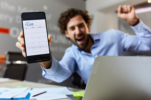 Close up of a free calendar on cell phone held by cheerful businessman in the office.