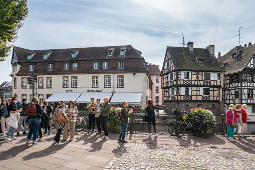 Strasbourg, France - September 22, 2021: People crowding up next to the channel side. Some taking photos, others admiring the view towards the half-timbered houses located across the channel