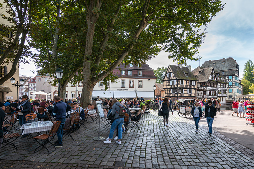 Strasbourg, France - September 22, 2021: People crowding up next to the channel side. Some taking photos, others admiring the view towards the half-timbered houses located across the channel