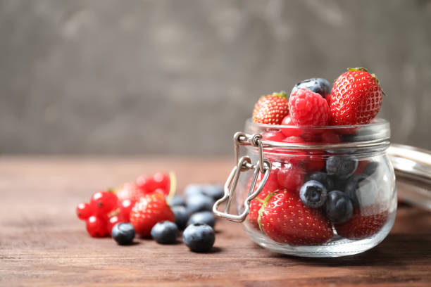 istock Mix of ripe berries on wooden table. Space for text 1353967652