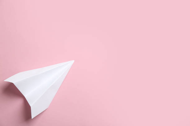 istock White paper plane on pink background, top view. Space for text 1353967655