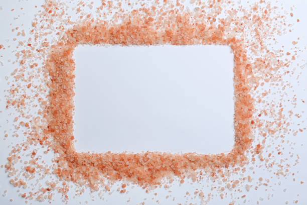 istock Frame of pink himalayan salt on white background, top view. Space for text 1353968246