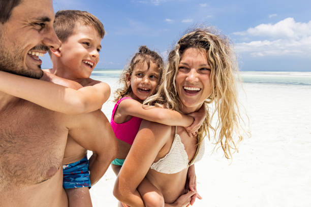 istock Happy family having fun while piggybacking on the beach. 1353968256