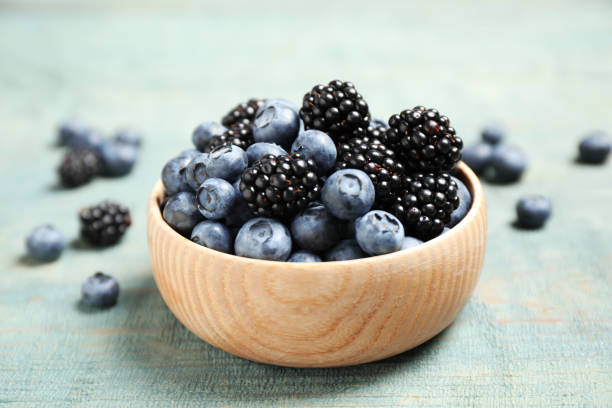 istock Blueberries and blackberries on blue wooden table 1353968442