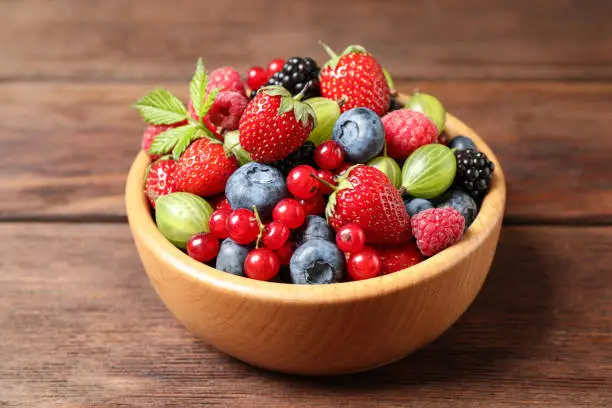 Mix of ripe berries on wooden table