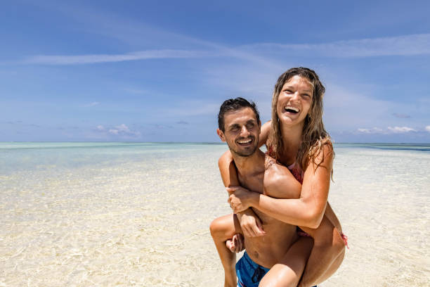 istock Happy couple having fun while piggybacking on the beach. 1353968720
