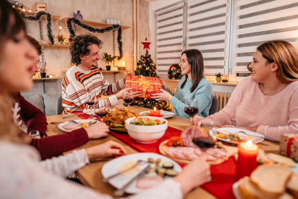 istock Friends exchanging Christmas gifts at dinner 1353969406