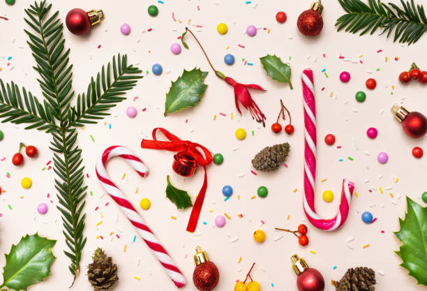 Awesome party inspired concept. Lovely Christmas pattern made of candy canes, pine cone, pine branches, red berries, colorful sugar coated round chocolate balls. Champagne background