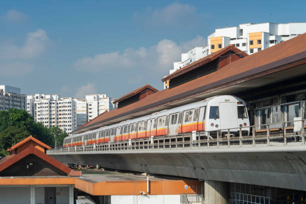 Public commuter train at Boon Lay MRT Station, Singapore Public commuter train leaving Boon Lay MRT Station on a sunny morning in Singapore, with HDB public housing apartment blocks in the background. singapore mrt stock pictures, royalty-free photos & images