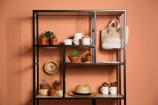 istock Stylish shelving unit with decorative elements near color wall. Interior design 1353972424