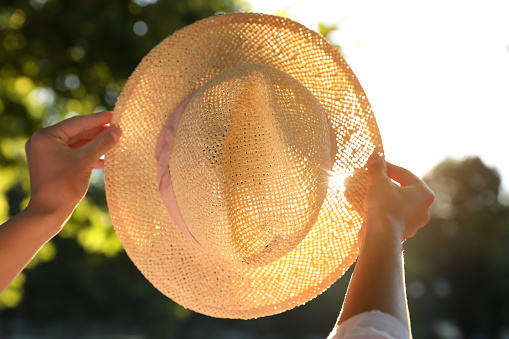 Young woman with straw hat outdoors on sunny day, closeup