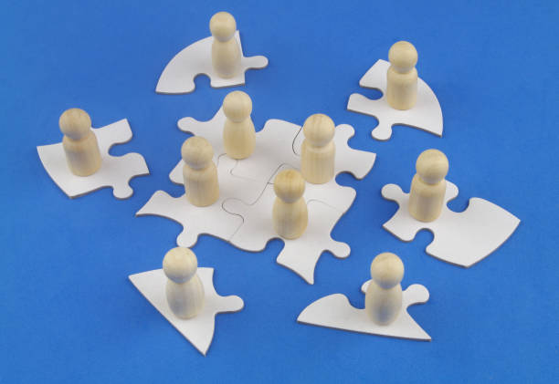 istock Wooden people figures on white jigsaw puzzle pieces. 1353972707