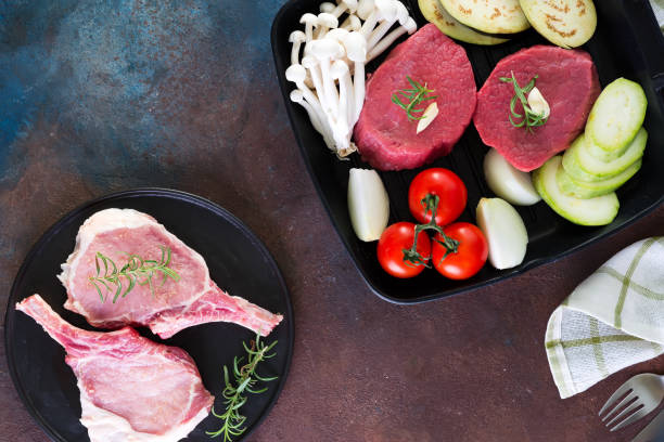 istock Raw beef steak on the bone with fresh vegetables in a grill pan on a concrete background, top view 1353974600