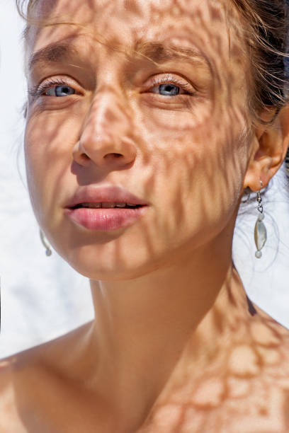 Headshot of a female face behind summer shadow