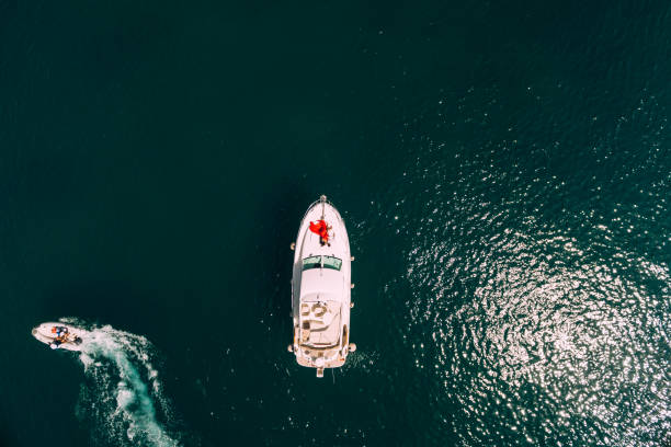 mulher de vestido vermelho está na proa de um iate a motor branco navegando no mar. ver de cima - nautical vessel motorboat speedboat people - fotografias e filmes do acervo