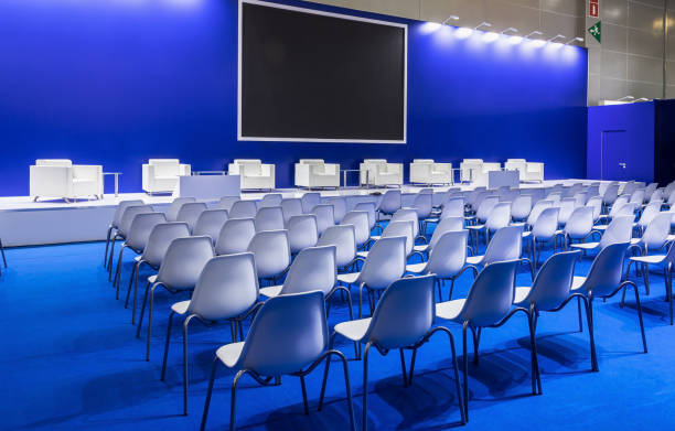 istock Conference Meeting Room, Row of White Chairs, with Stage and Empty Screen 1353979563