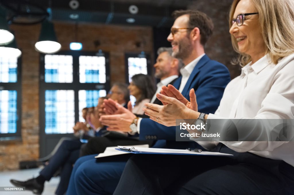 Business seminar Group of business people sitting on chairs in the convention center and clapping hands. Close up of human hand. Unrecognizable people. Laughing Stock Photo