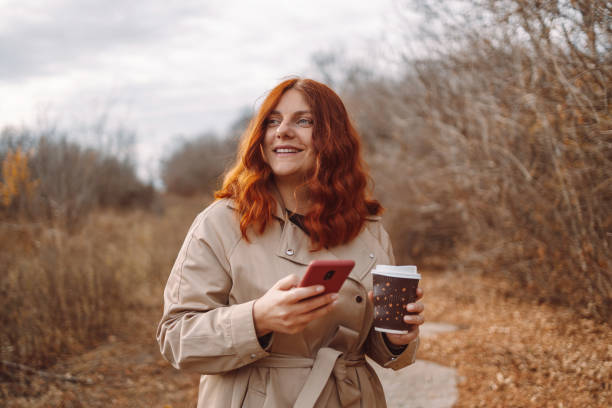istock Beautiful young woman using smartphone and drinking coffee takeaway 1353981254