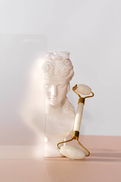 istock White marble head of a young woman with a face roller 1353981419