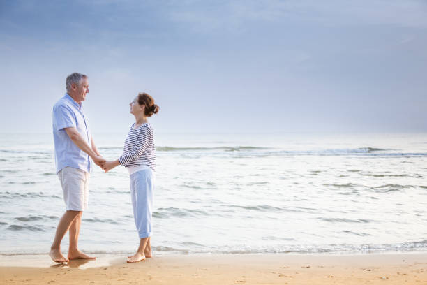 istock Active senior couple walking on the beach 1353986369