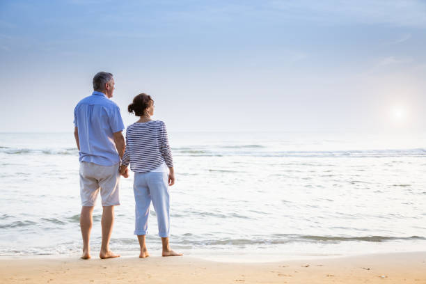 istock Active senior couple walking on the beach 1353986376