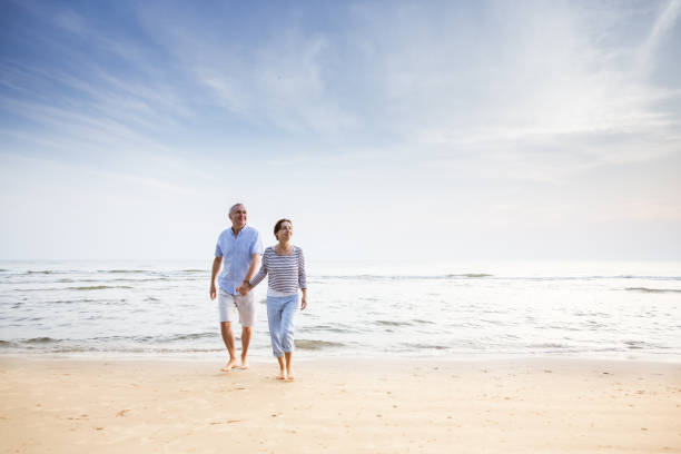 istock Active senior couple walking on the beach 1353986429