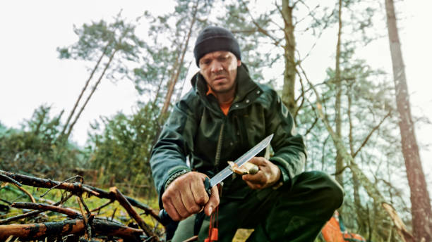 istock Man sharpening the end of branch in forest 1353987008
