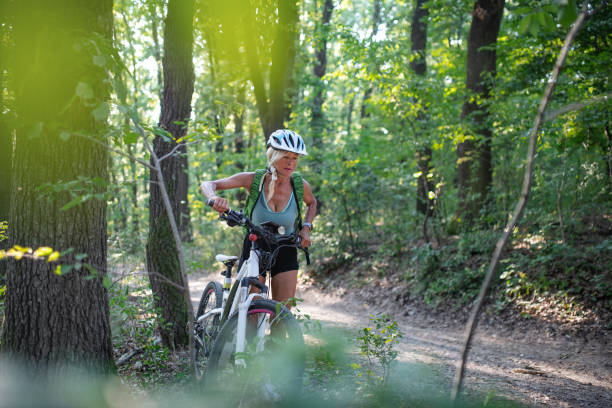 istock Active senior woman biker pushing ebike outdoors in forest. 1353987865