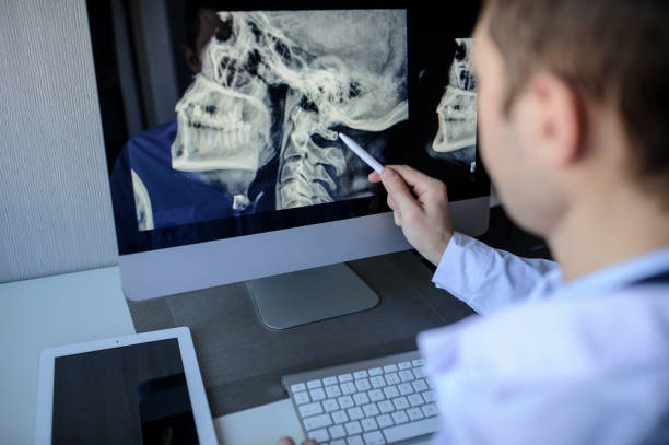 male radiologist examining x-rays on computer back view of a male radiologist examining neck x-rays (cervical vertebrae) on computer cervical vertebrae photos stock pictures, royalty-free photos & images