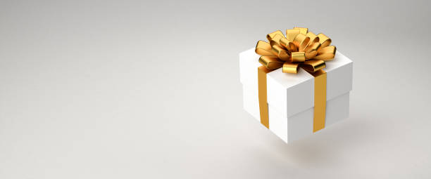 istock A white gift box with golden ribbon and bow hovering over a white background. Copy space - web banner format. 1353990562