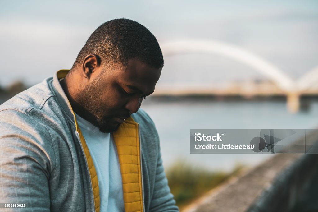Depressed black man Depressed black man sitting outdoor. Depression - Sadness Stock Photo