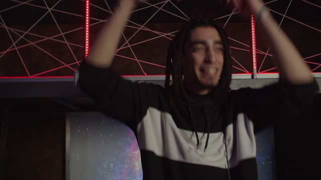 Portrait of energetic cool dj in headphones cheering up people during live set in nightclub