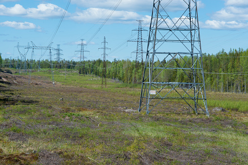 Power lines on the field - a string of towers of different shapes in a space cut into the rock - electricity in Finland