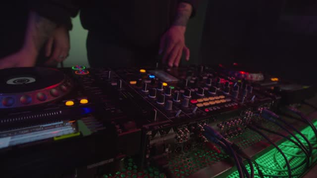 Professional multiethnic male djs mixing musical track using modern sound mixer at stage