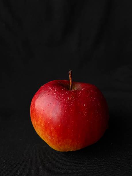 istock Red apple with water drops on a black background 1353993129