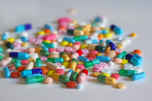 красочные капсулы, таблетки и таблетки на белом столе, лечение - painkiller pill capsule birth control pill стоковые фото и изображения