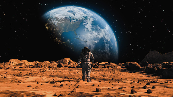 Después de la toma de un valiente astronauta con traje espacial caminando con confianza sobre Marte hacia la Tierra, un planeta rojo alienígena cubierto de rocas. Primer astronauta en Marte. Tecnologías avanzadas, exploración espacial / viajes, concept photo