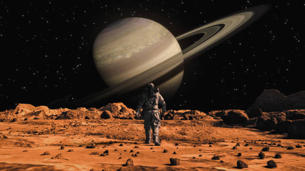 Following Shot of Brave Astronaut in Space Suit Confidently Walking on Mars Towards Saturn Planet. Saturn seen from Mars surface. The surface of Mars, strewn with small rocks and red sand. Martian landscape in rusty orange shades, Mars Planet surface, Desert, Cliffs, sand. Red planet mars. Alien Red Planet Covered in Rocks. First Astronaut On the Mars. Big Moment for the Human Race. Advanced Technologies, Space Exploration/ Travel, Colonization Concept. después de la toma de un valiente astronauta con traje espacial caminando con confianza sobre marte hacia saturno, un planeta rojo alienígena cubierto de rocas. primer astronauta en marte. tecnologías avanzadas, exploración espacial / viajes, concepto