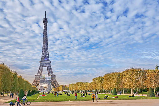 Paris, France - September 30, 2021:  Pedestrians in the Champ de Mars Park in Paris. In the background the Eiffel Tower.