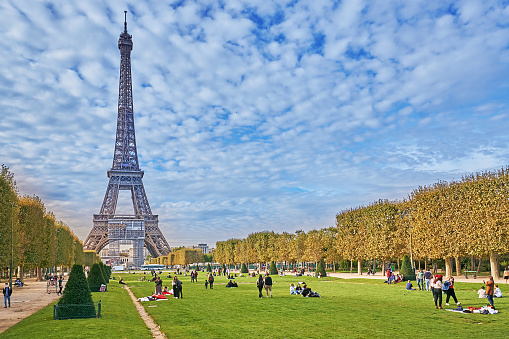 Paris, France - September 30, 2021:  Pedestrians in the Champ de Mars Park in Paris. In the background the Eiffel Tower.