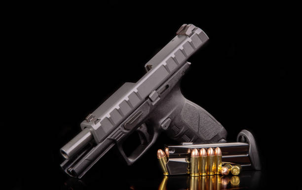istock Discharged weapon. Black modern gun and ammunition for it on a dark reflective surface. Short-barreled weapons for sports and self-defense. Armament for police units, special forces and the army. 1354001732