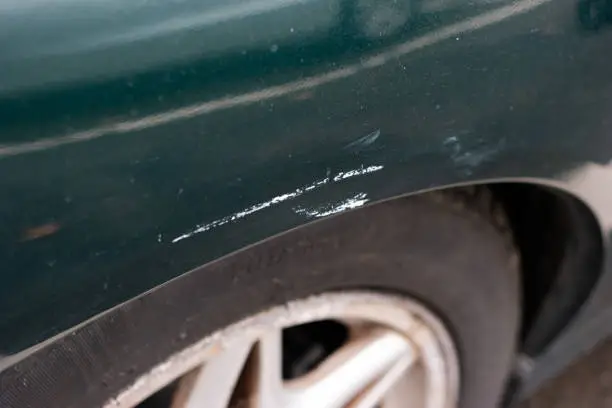 Car wheel arch paint damage. Small scratch white pant transfer from parking space poll. Close up shot, no peop.