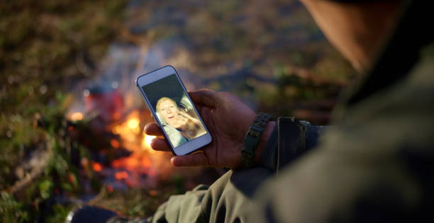 istock Man sitting by the campfire and making a video call 1354005197