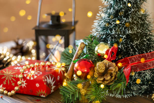 istock Close-up Christmas festive background with a Christmas tree decorated with balls, pine cone with gold lights, gifts wrapped in paper, candles on a wooden table close-up 1354005730