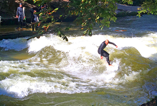 Young man surfing in river Isar, Munich, Germany.