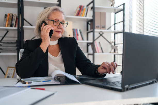 istock Beautiful elderly businesswoman speaking on smart phone while working 1354015128